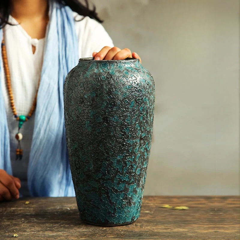 a woman is holding a green vase on a table