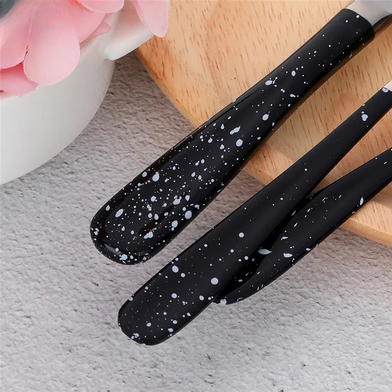 three black spatulas sitting on top of a wooden cutting board