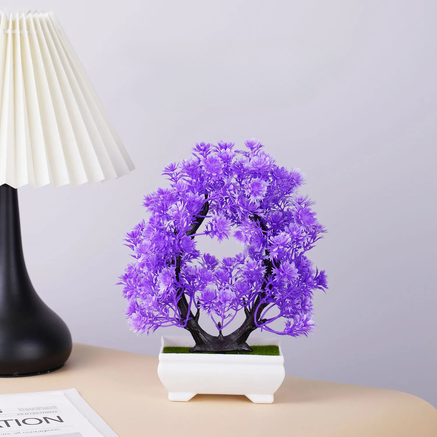 a purple bonsai tree in a white vase next to a black lamp