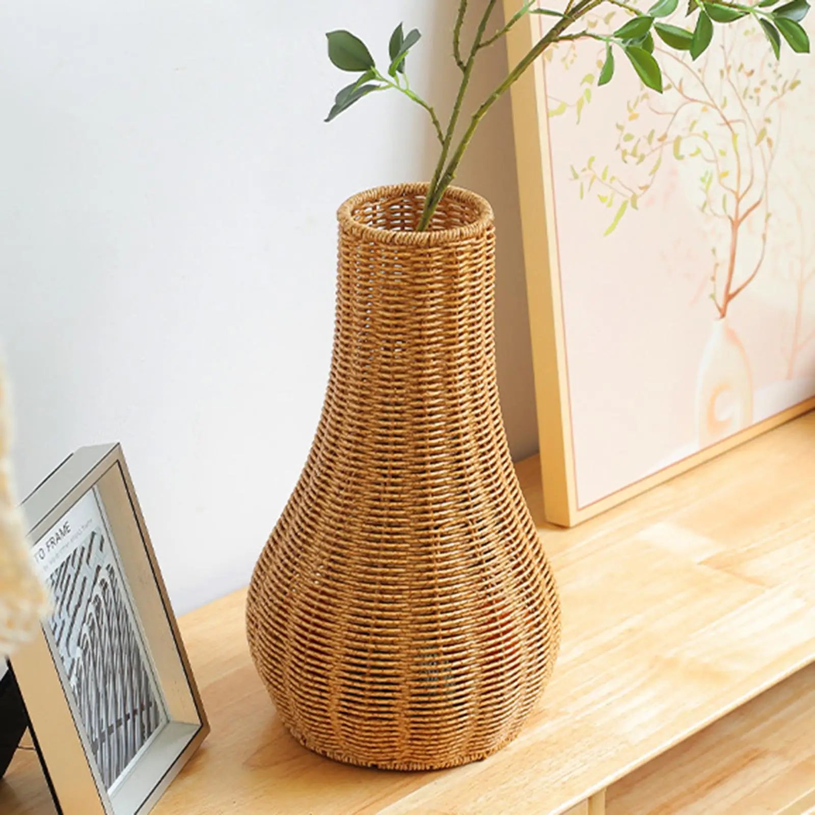 a wicker vase sitting on a table next to a picture frame