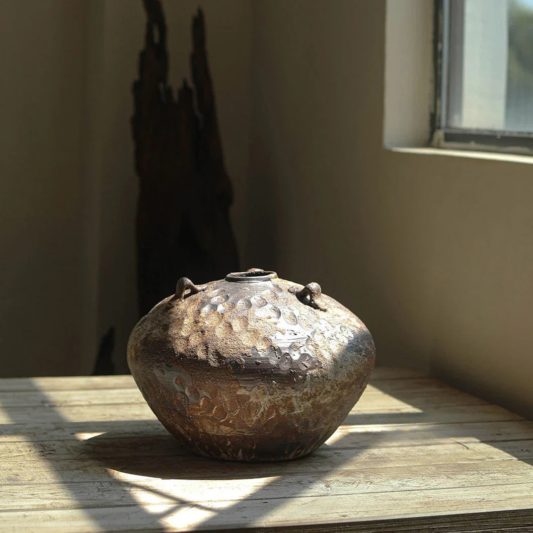 a brown vase sitting on top of a wooden table