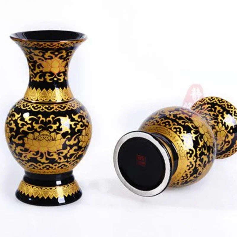 a black and gold vase sitting next to another vase